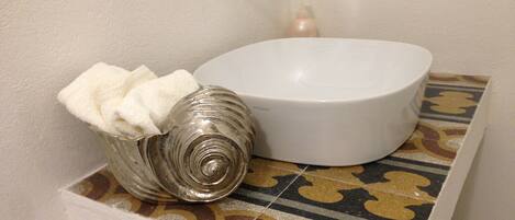 A bathroom with a white ceramic sink, a decorative shell, and a patterned tile backsplash.