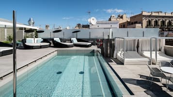 Un área de piscina en la azotea con sillas de descanso, una piscina pequeña y vistas de la ciudad.