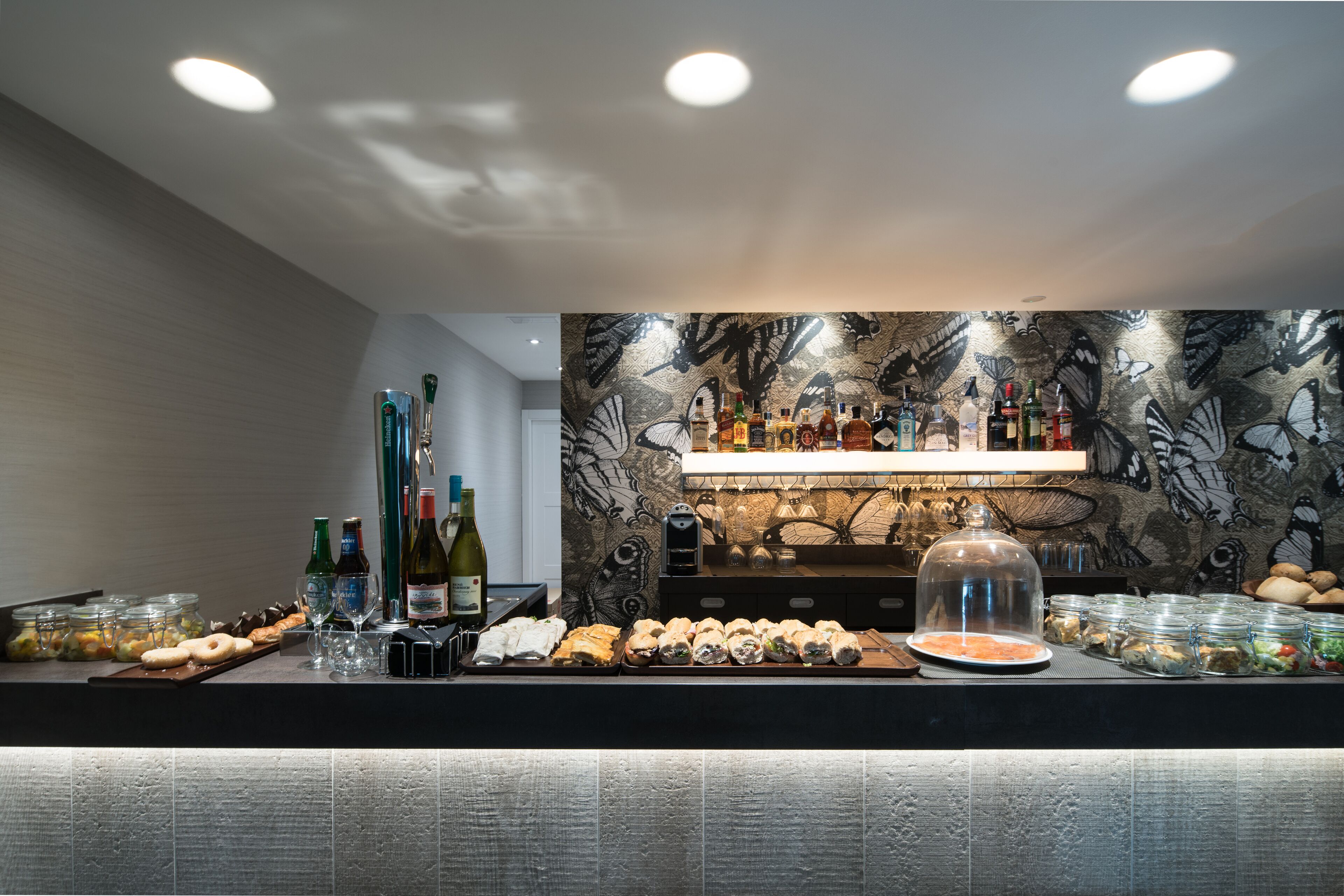 Zona de bar con una variedad de botellas, vasos y alimentos.