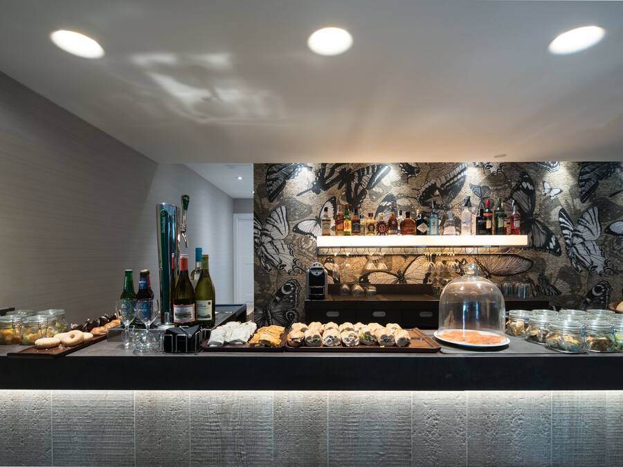 Zona de bar con una variedad de botellas, vasos y alimentos.