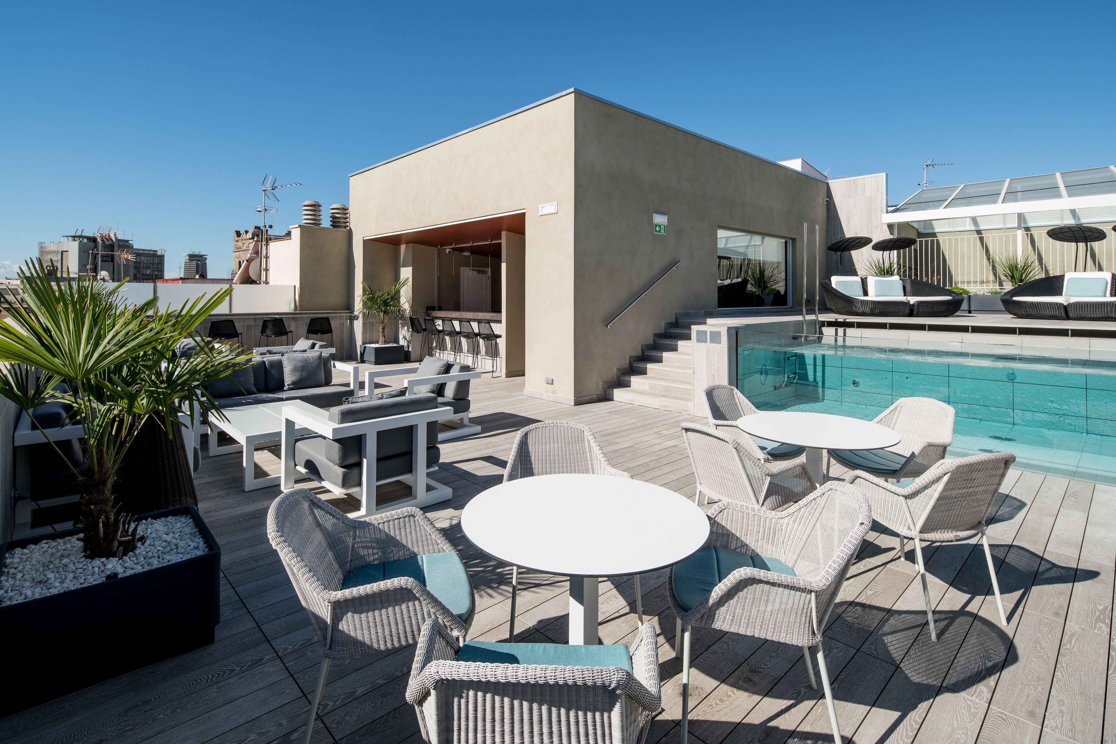 A rooftop pool area with outdoor seating and a staircase leading to an upper level.