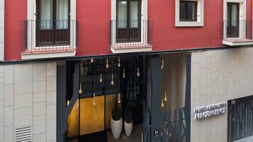 Fachada de hotel roja, con varios balcones e iluminación colgante.