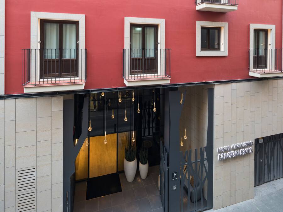 Fachada de hotel roja, con varios balcones e iluminación colgante.