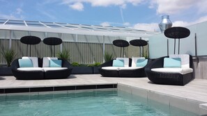 A poolside area with three black wicker lounge chairs, each with a white cushion and a light blue pillow. - Catalonia Magdalenes (Barcelona)