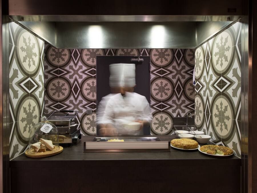 Una estación de cocina con salpicadero de azulejos, un extractor de humos y varios alimentos expuestos sobre la encimera.
