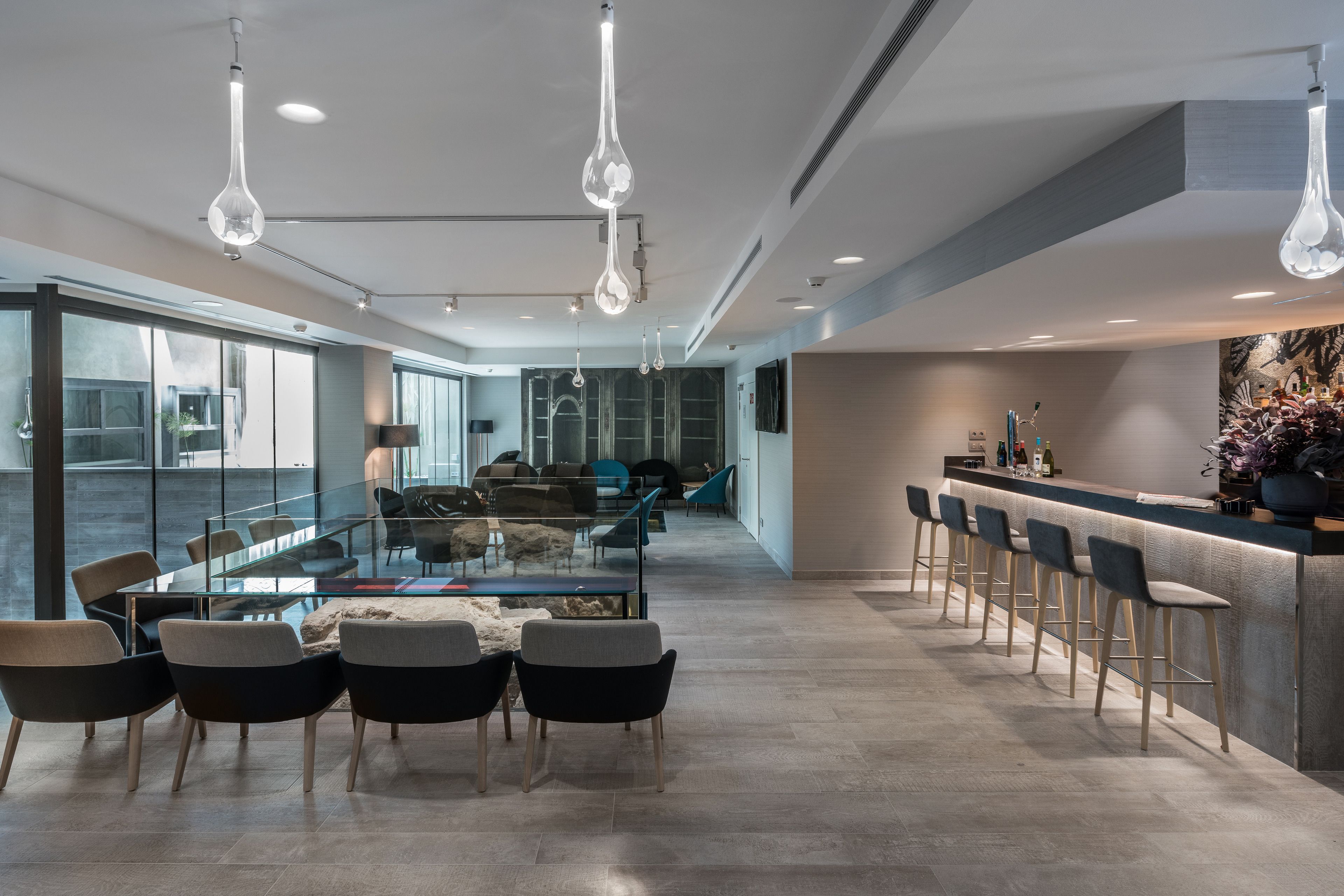 A modern kitchen with a bar area, large windows, and contemporary lighting fixtures.
