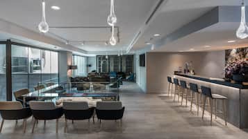 A modern kitchen with a bar area, large windows, and contemporary lighting fixtures.