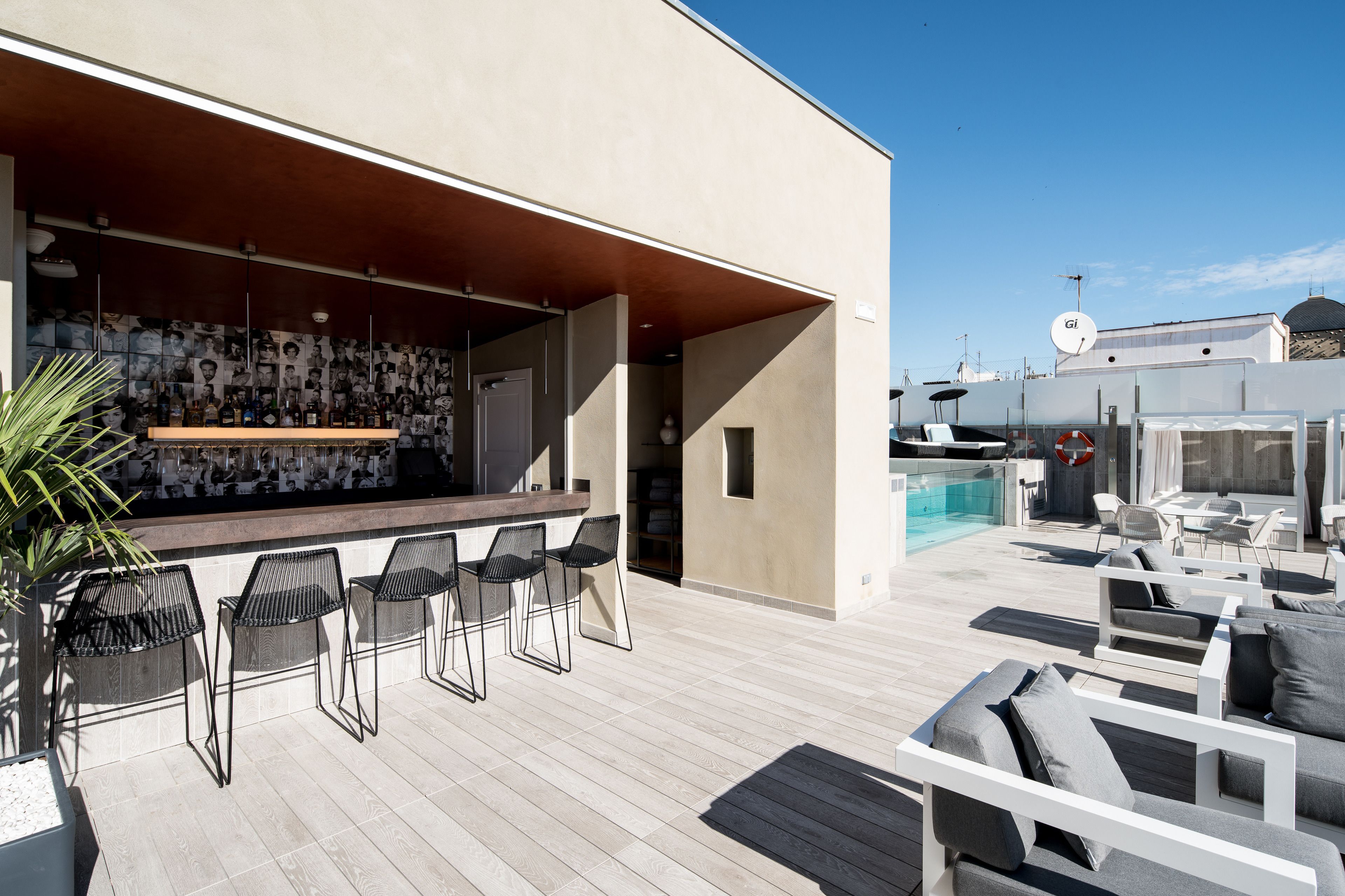 A modern outdoor bar area with a pool and lounge seating.