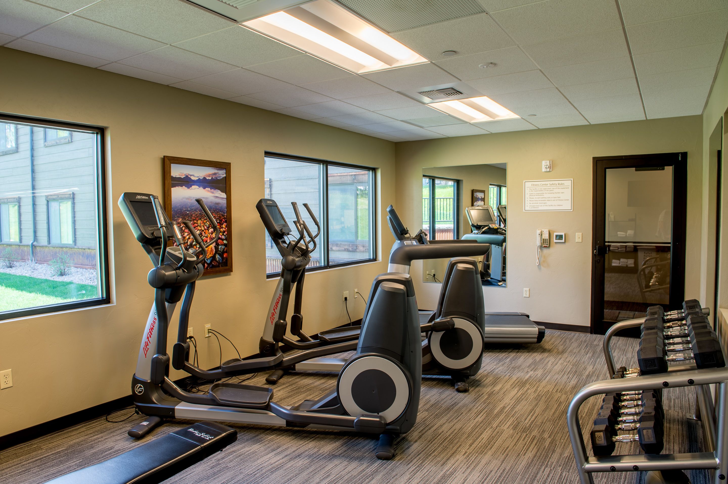 A gym with treadmills, elliptical machines, and a weight bench.