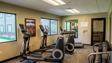 A gym with treadmills, elliptical machines, and a weight bench.