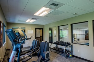 A gym with treadmills, elliptical machines, and a rack of dumbbells.