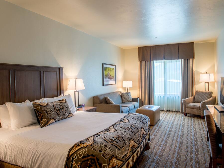 A hotel room with a large bed, two armchairs, a desk, and a sofa.