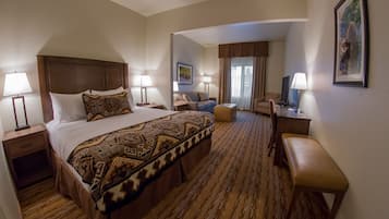 A hotel room with a large bed, two bedside tables, a desk, a chair, and a TV.