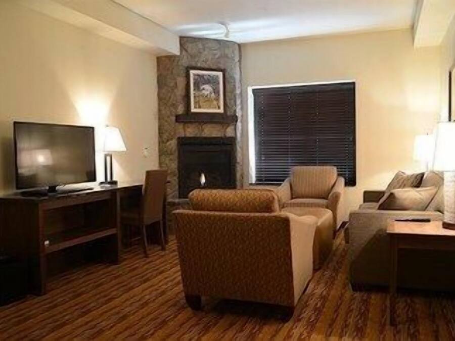 A living room with a television, two sofas, a fireplace, and a window with blinds.