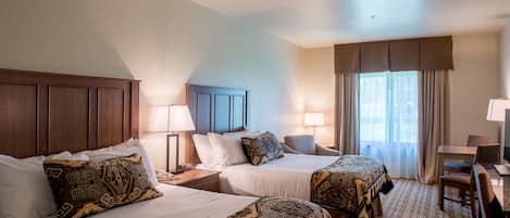 A hotel room with two beds, a desk, and a chair.