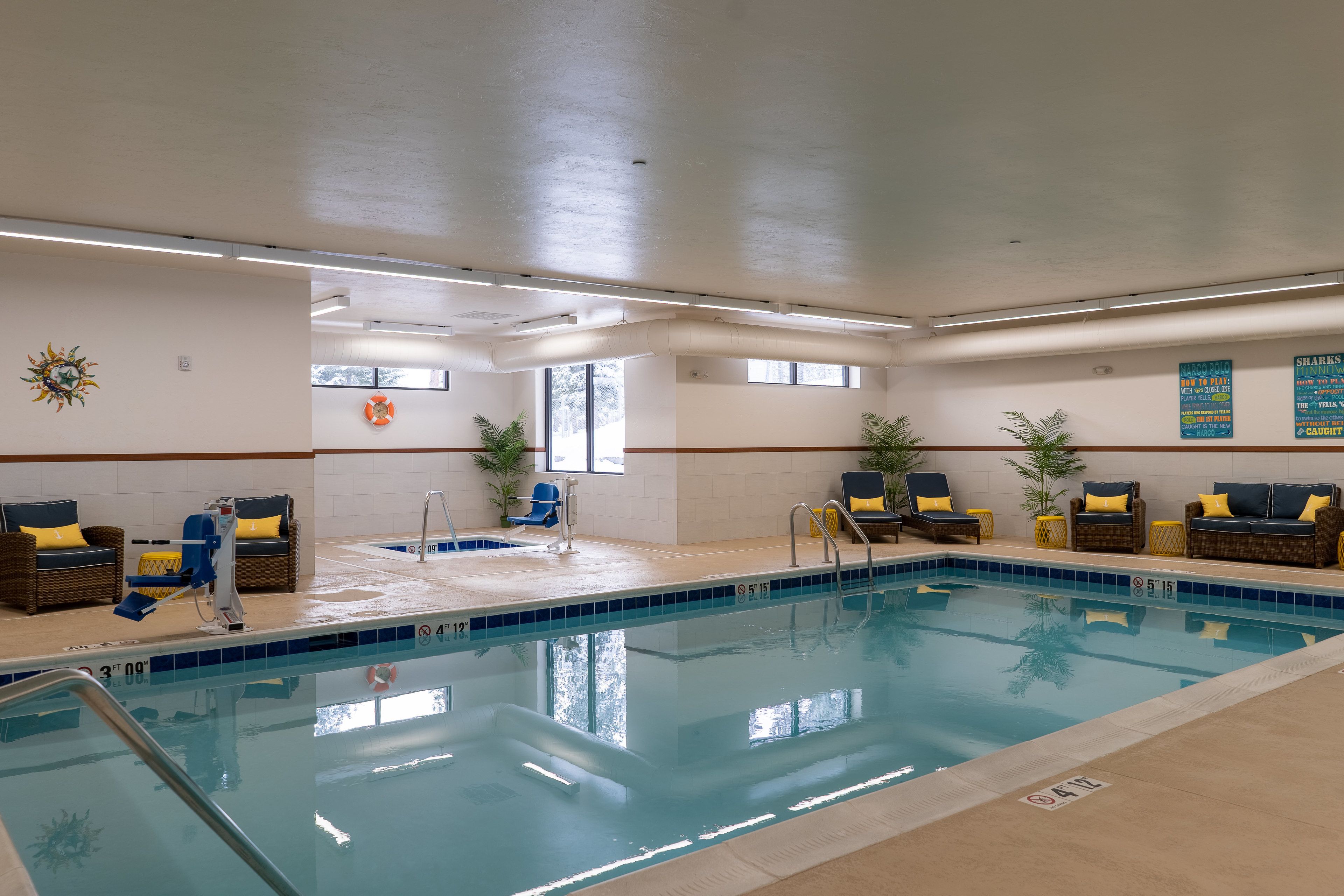 Une piscine intérieure dotée de chaises longues, d’une bouée de sauvetage et d’une décoration solaire sur le mur.
