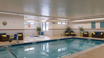 Une piscine intérieure dotée de chaises longues, d’une bouée de sauvetage et d’une décoration solaire sur le mur.
