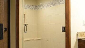 A shower with a glass door, a wooden frame, and a tiled wall.
