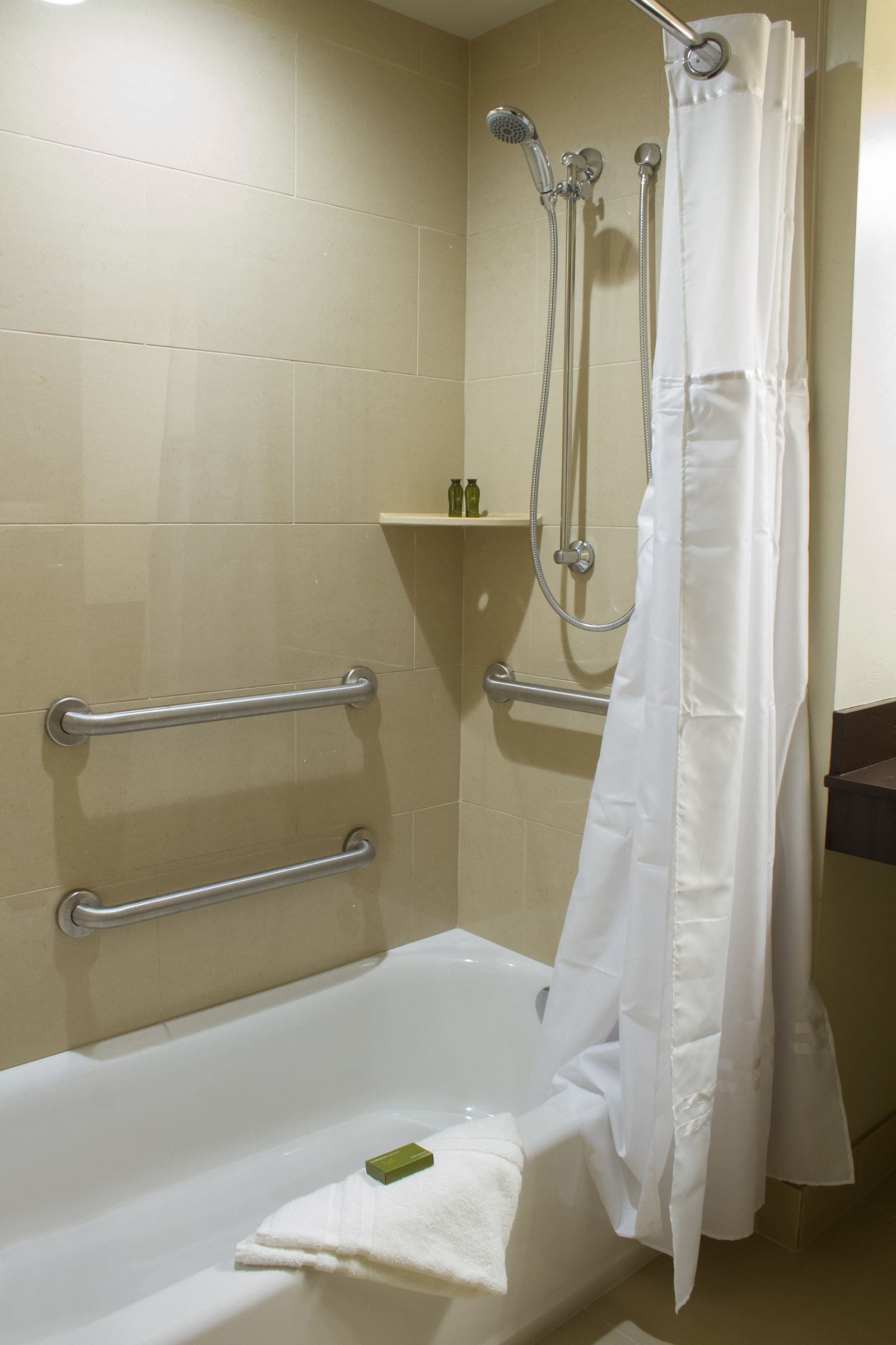 A bathroom with a bathtub, a shower with a curtain, and grab bars.