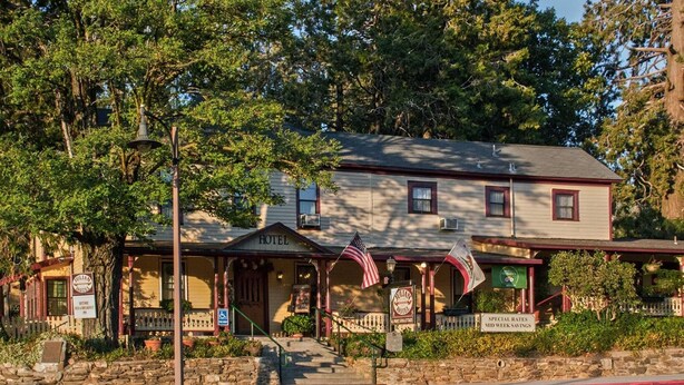 A historic hotel with a traditional facade, a front porch, and a sign indicating special rates mid-week savings. - Julian Gold Rush Hotel (Julian)