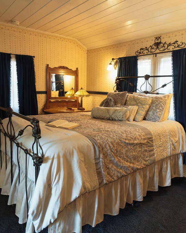 Classic four-poster bed with a decorative headboard and canopy, accompanied by a patterned bedspread and multiple pillows.