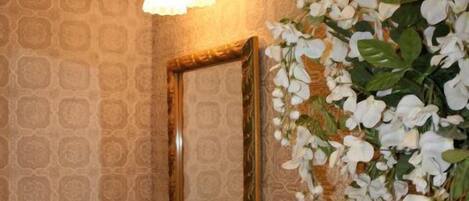 A bathroom with a sink, mirror, and decorative flowers.