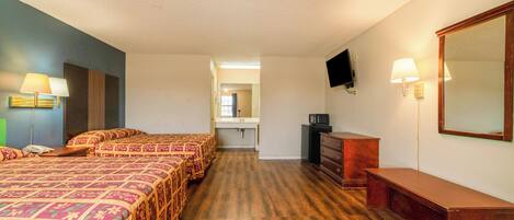 Een hotelkamer met twee bedden, een bureau, een dressoir, een televisie en een badkamer op de achtergrond.