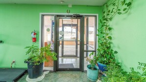 A green-walled entrance with a glass door, potted plants, and a fire extinguisher on the wall. - Executive Inn By OYO Mineral Wells US-180 (Mineral Wells)