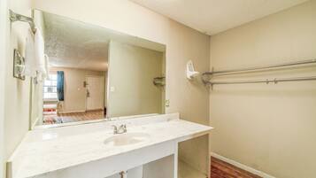 A bathroom with a white sink, a large mirror, and a towel rack.
