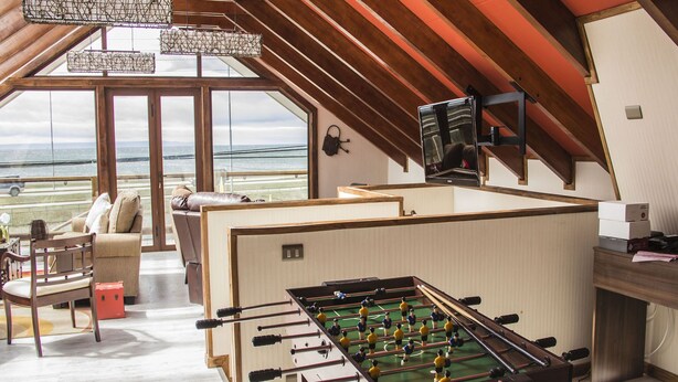 A spacious room with a foosball table, a sofa, and a television.