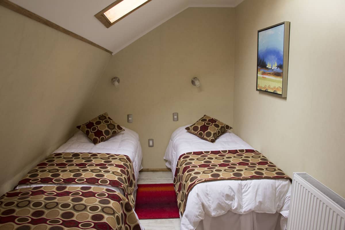 A room with two beds, a red carpet, a painting on the wall, and a radiator.