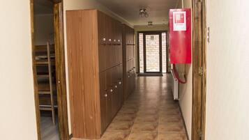 Pasillo con armarios de madera, un detector de incendios rojo y vista al exterior a través de una puerta de cristal.
