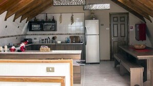 A kitchen with wooden beams, a microwave, a refrigerator, and a wooden dining table.