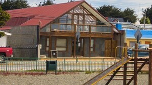 A building under construction with a red roof, a wooden structure, and a playground with a slide.