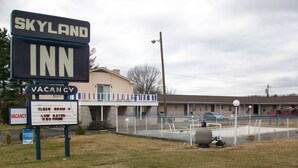 Un motel llamado Skyland Inn con un letrero que indica habitaciones disponibles y servicios como habitaciones limpias, tarifas bajas y teléfono.