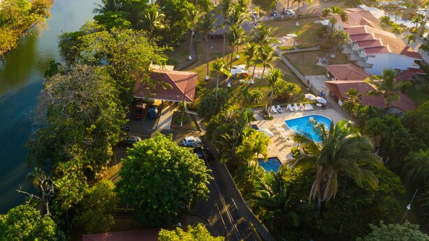 Ett flygbildsfoto av ett semesterområde med en swimmingpool, palmer och tillgång till stranden.