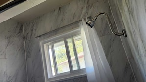 A bathroom with a shower, a window, and a view of greenery outside. -  Random Lake Motel (RLM) (Random Lake)