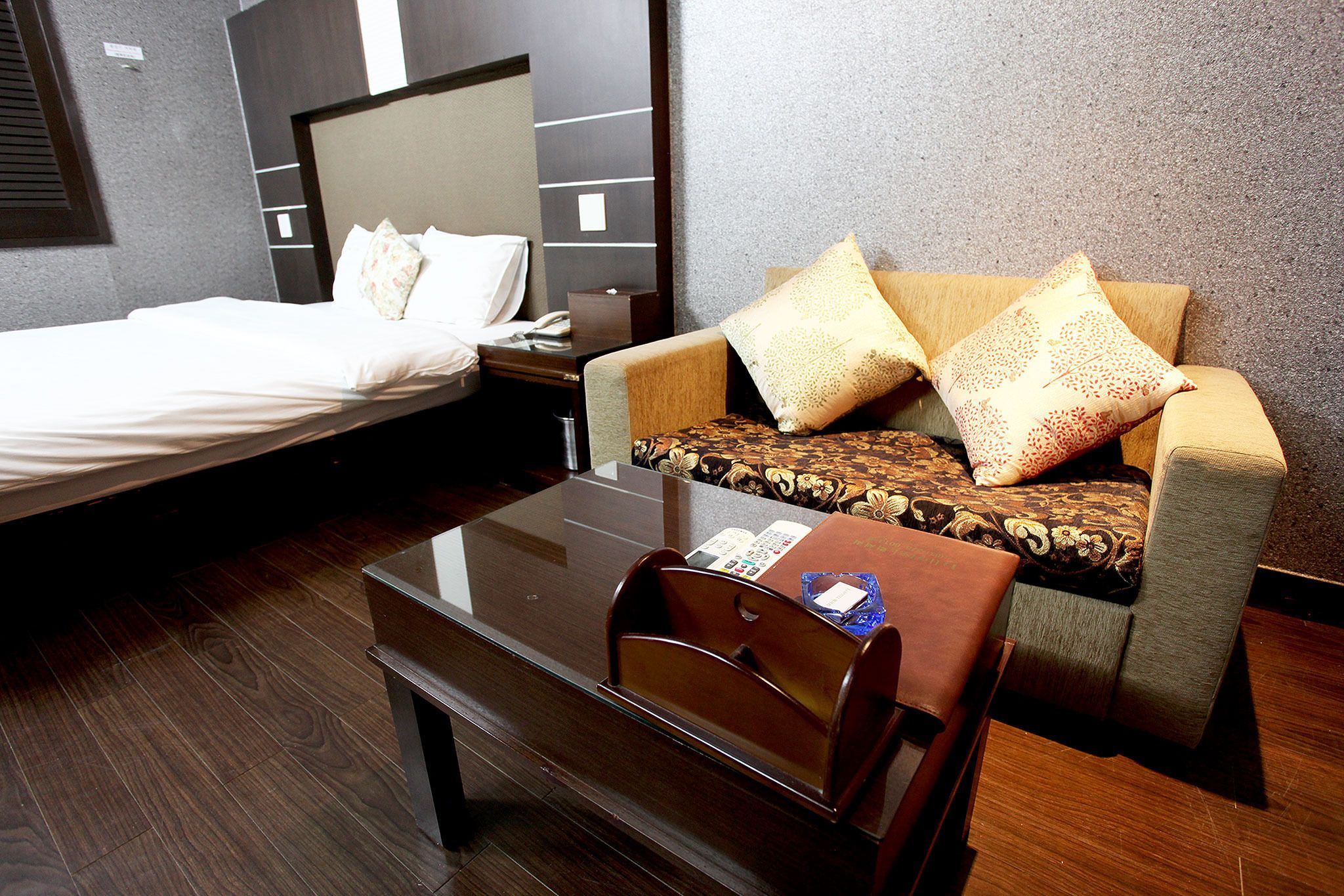 A hotel room with a bed, a sofa, a coffee table, and a nightstand.