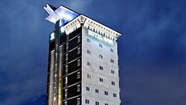 A tall hotel with multiple floors and a distinctive top structure.