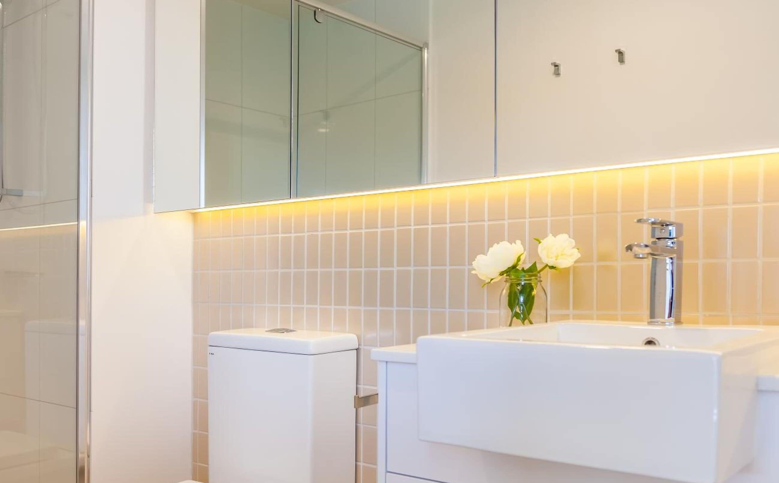 A modern bathroom with a toilet, sink, and mirror.