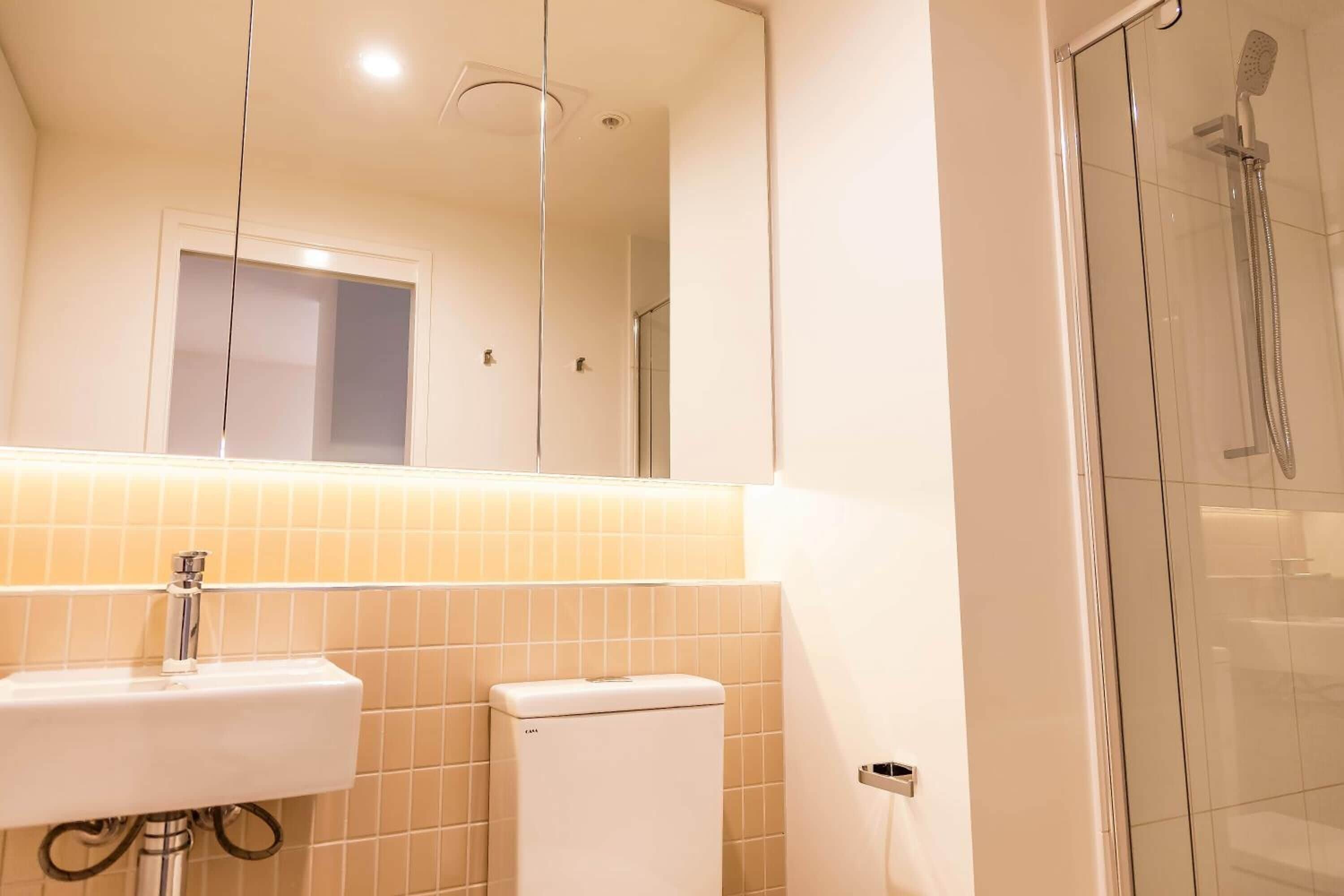 A bathroom with a white sink, a toilet, and a glass shower enclosure.