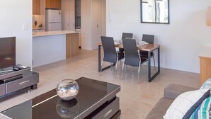 Una sala de estar moderna con un televisor de pantalla plana, una mesa de centro con un cuenco decorativo y un sofá con un cojín.