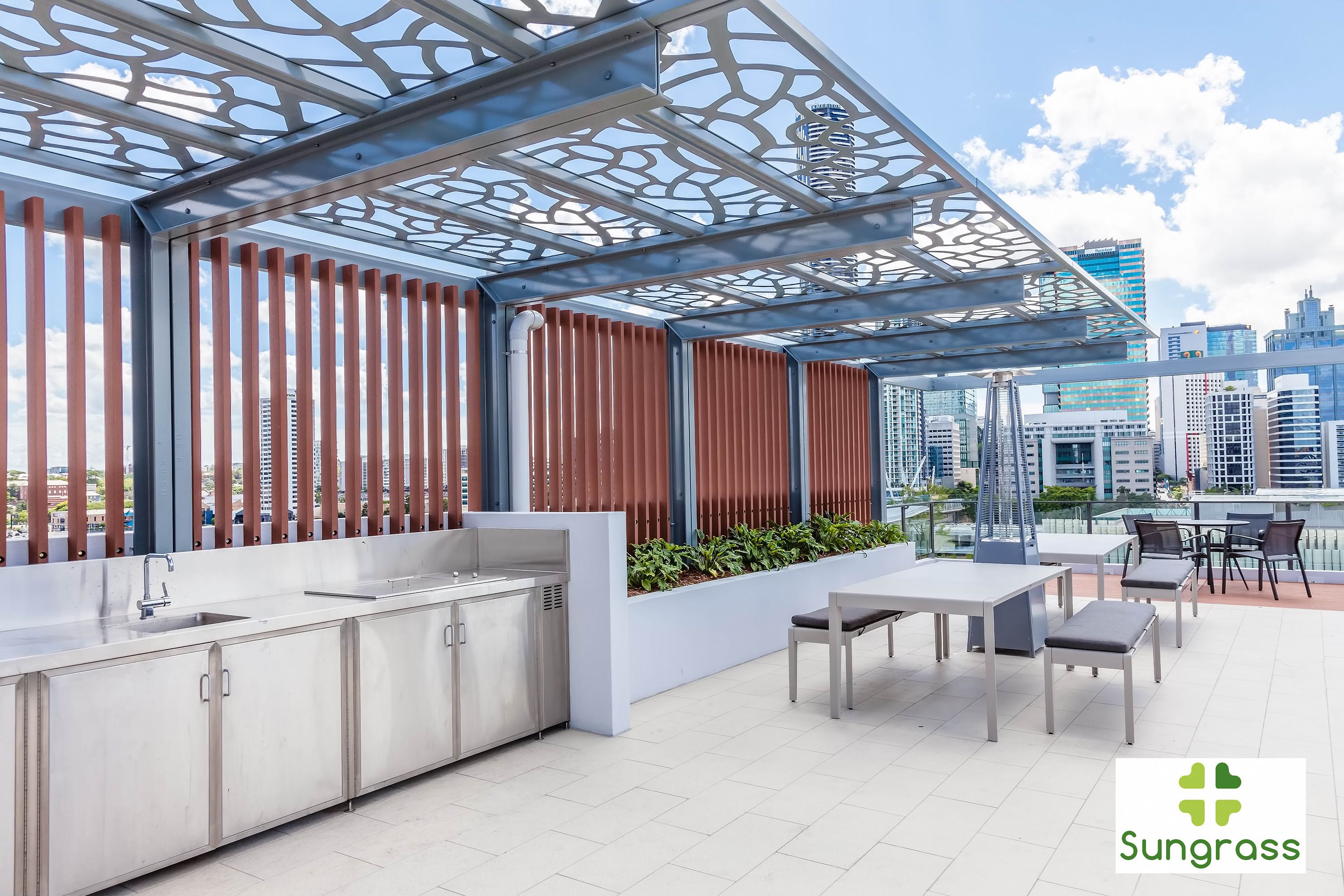 A rooftop patio with a modern kitchen, outdoor seating, and a city view.