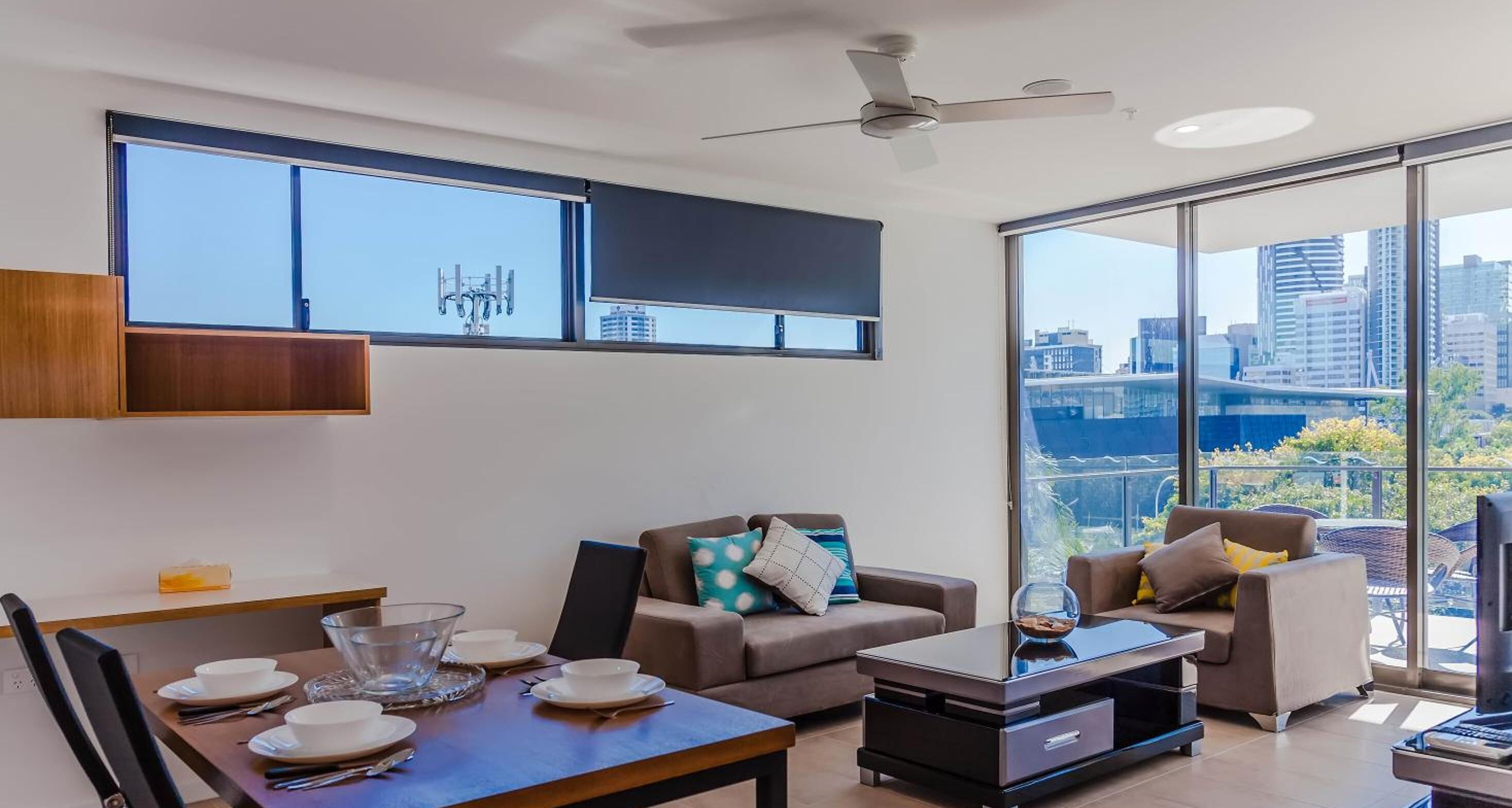 Una sala de estar moderna con comedor, ventanas amplias y vistas a la ciudad.