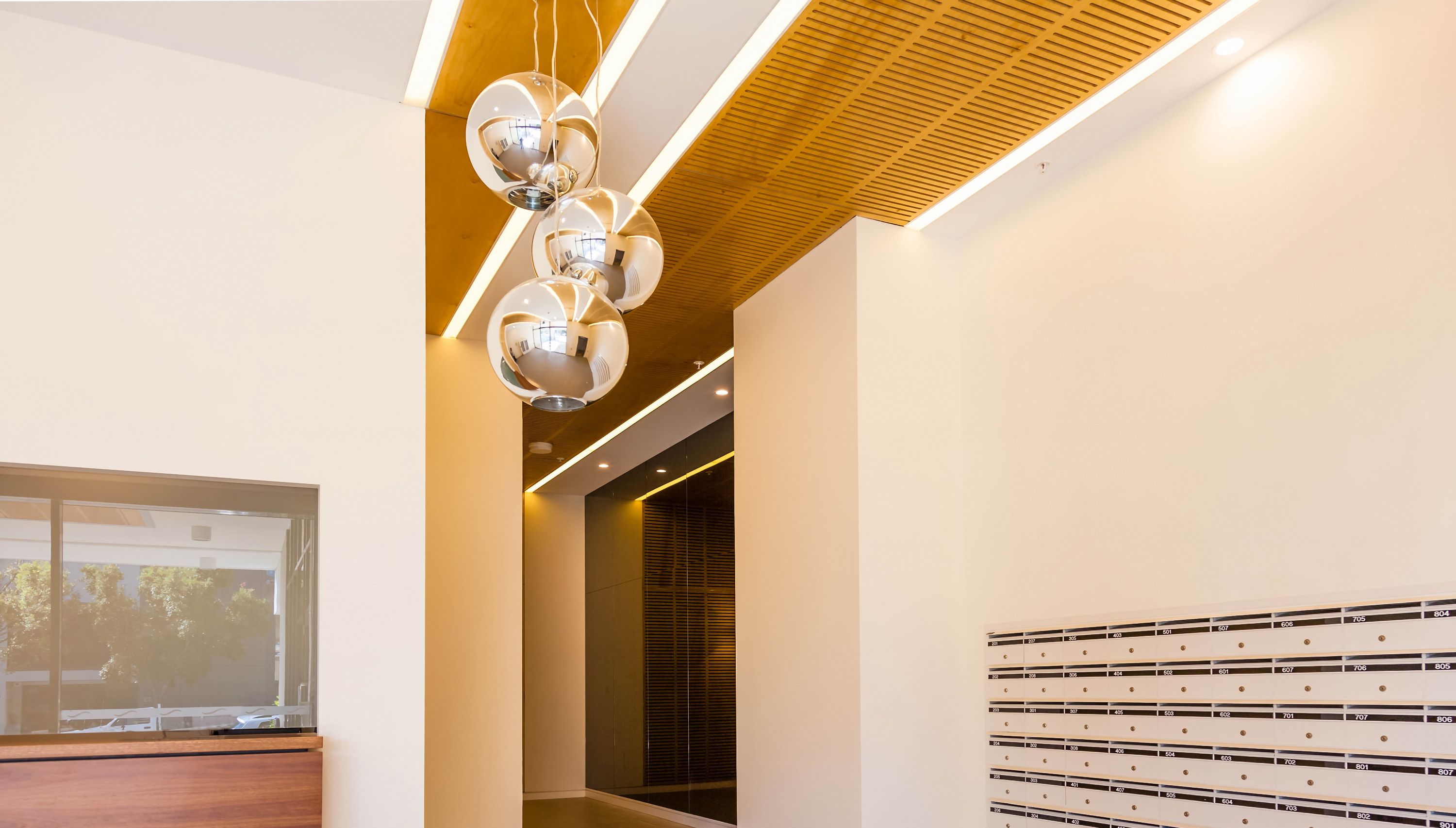 A modern interior with a wooden ceiling, a glass wall, and a wall with numbered storage units.