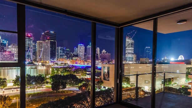 Un horizonte urbano nocturno con edificios iluminados y un río.