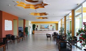 A hotel lobby with a reception desk, chairs, and a large window.