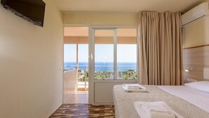 Une chambre d’hôtel avec un lit, une télévision, un balcon avec vue et une porte coulissante.