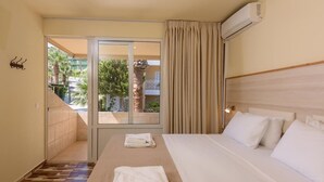 Une chambre d’hôtel avec un lit, une porte-fenêtre coulissante donnant sur le balcon et un appareil de climatisation.