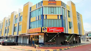 Ett hotell med en gul och blå fasad, en skylt med texten ”Sun Inns International” och en restaurang som heter ”Johnny Sizzling House”.
